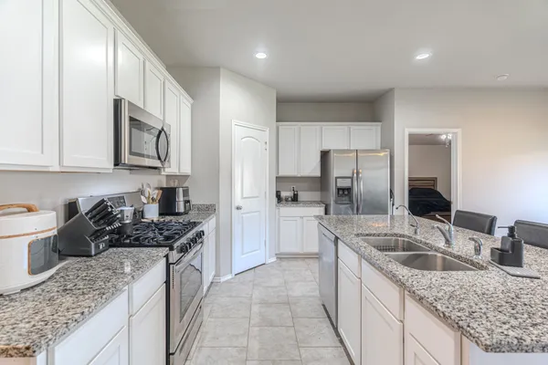 a kitchen with stainless steel appliances granite countertop a sink stove refrigerator and cabinets