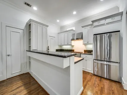 a kitchen with granite countertop a refrigerator and a stove top oven