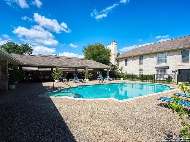 a view of swimming pool with lawn chairs and plants