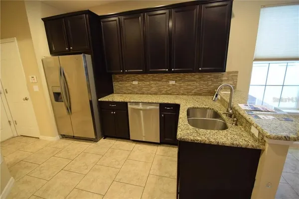 a kitchen with granite countertop a refrigerator a stove a sink dishwasher and wooden cabinets