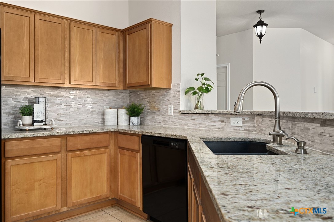 a kitchen with granite countertop a sink a stove and cabinets
