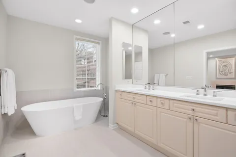 a spacious bathroom with a double vanity sink a mirror and a bathtub