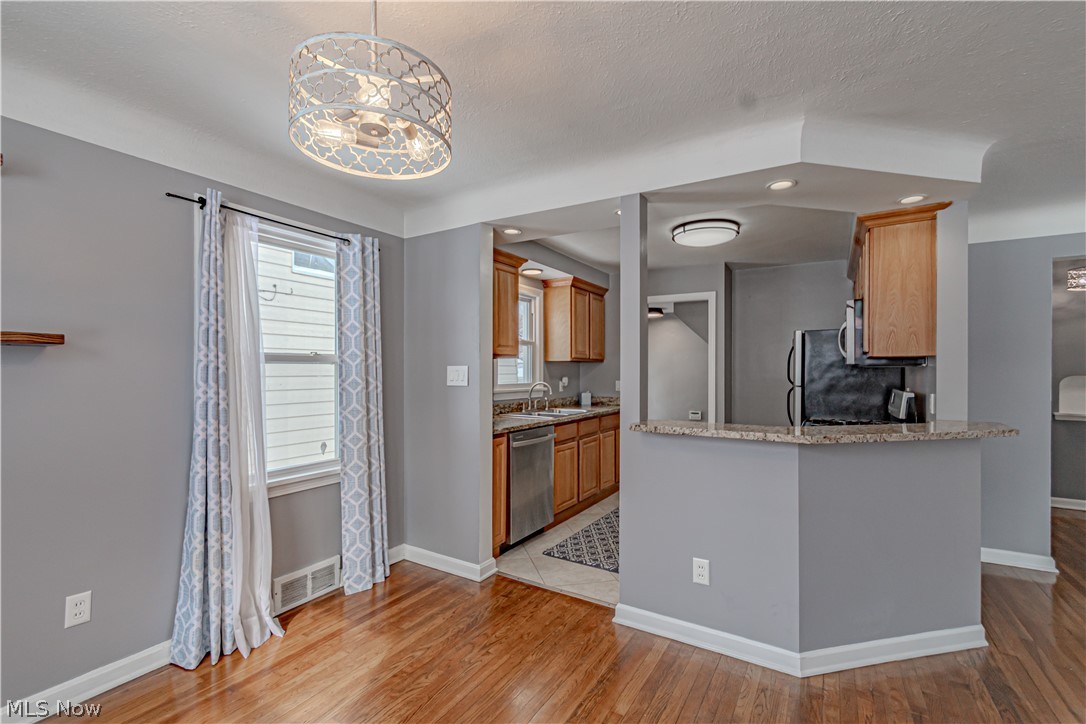4157 Verona Road Cleveland, OH 44121 - Photo 7 of 26 Kitchen with light stone counters, stainless steel dishwasher, light wood-type flooring, a peninsula, and a textured ceiling