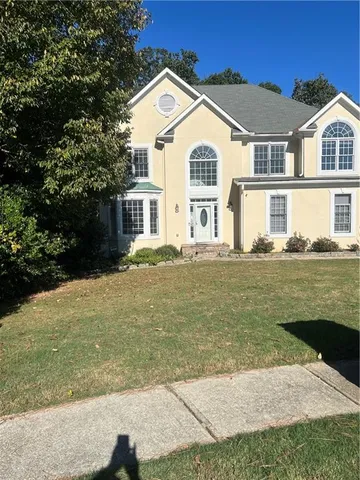 a view of a white house next to a yard with big trees