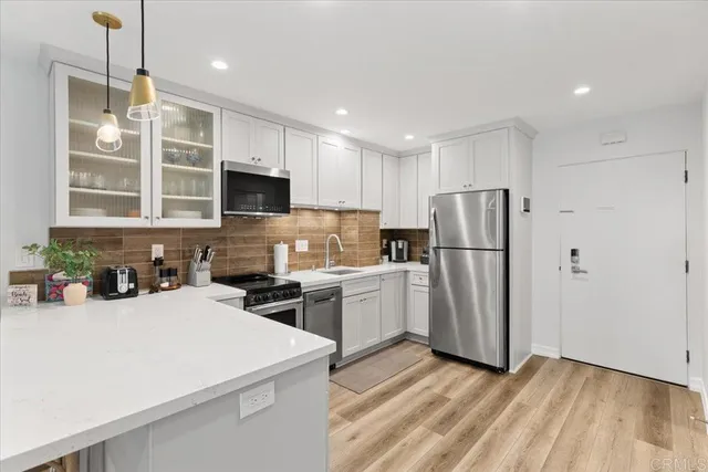 a kitchen with a refrigerator a microwave oven a sink and dishwasher with wooden floor