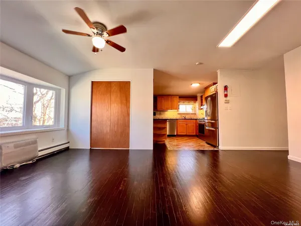 a view of a room with wooden floor a ceiling fan and windows