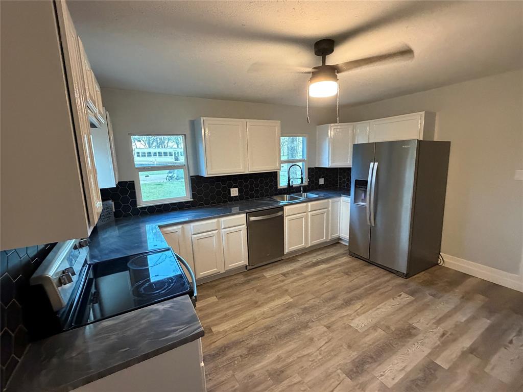 150 Ash Creek Court Springtown, TX 76082 - Photo 4 of 20 Kitchen with epoxy countertops, stainless steel appliances, backsplash, light wood-type flooring, and white cabinets