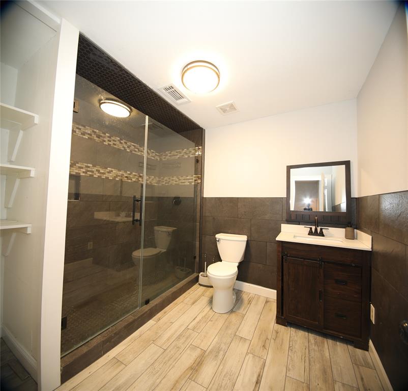 150 Ash Creek Court Springtown, TX 76082 - Photo 8 of 20 Full bathroom featuring vanity, tile walls, light wood finished floors, and a shower stall