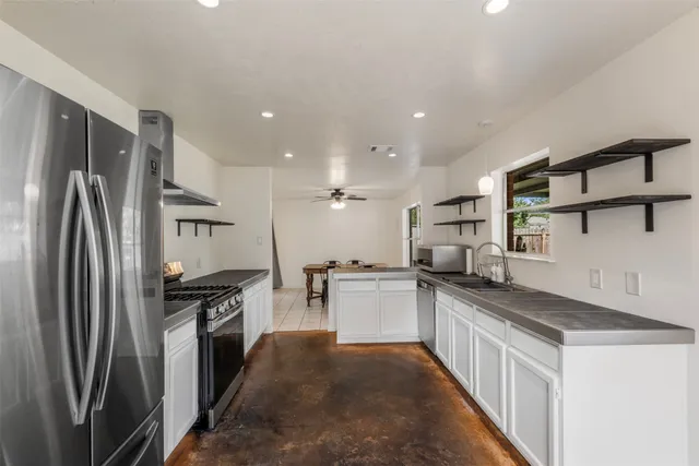 a kitchen with stainless steel appliances granite countertop a refrigerator and a stove top oven