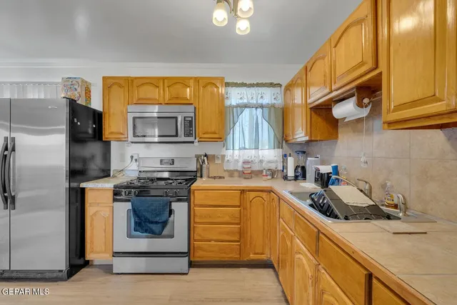 a kitchen with stainless steel appliances granite countertop a sink a stove and a refrigerator