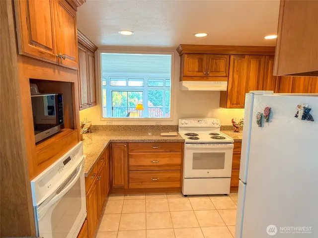 a kitchen with granite countertop a stove a sink and a refrigerator