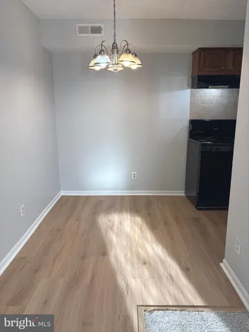 a view of kitchen and empty room with wooden floor