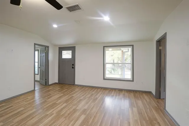 a view of an empty room with wooden floor and window