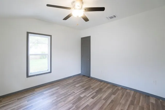 a view of a bedroom with wooden floor and window