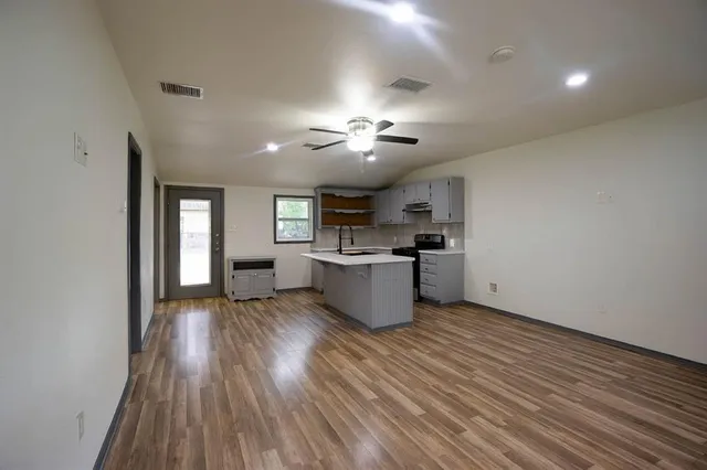 a view of an empty room with window and wooden floor