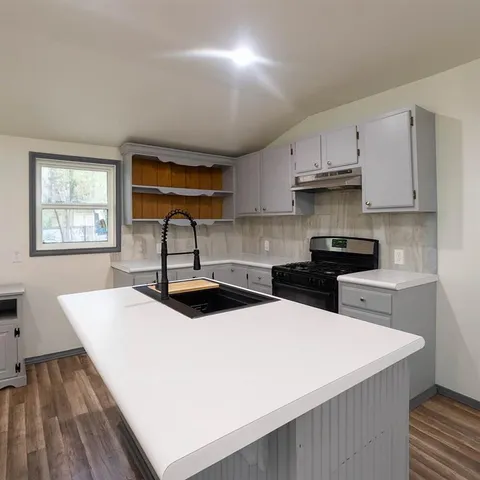 a kitchen with stainless steel appliances a sink a stove a refrigerator cabinets and a dining table