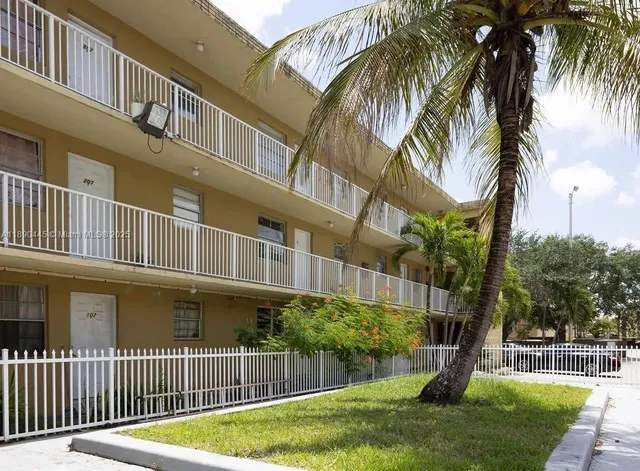 a view of a house with a yard and a palm tree