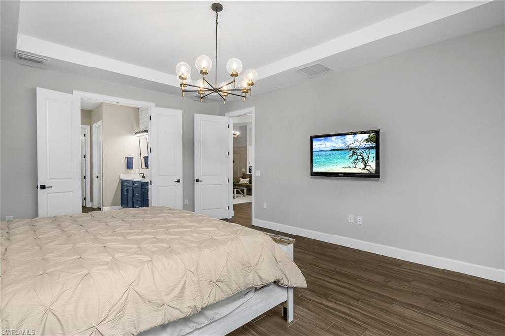 17570 Ashcomb Way Estero, FL 33928 - Photo 20 of 50 a spacious bedroom with a bed and a chandelier