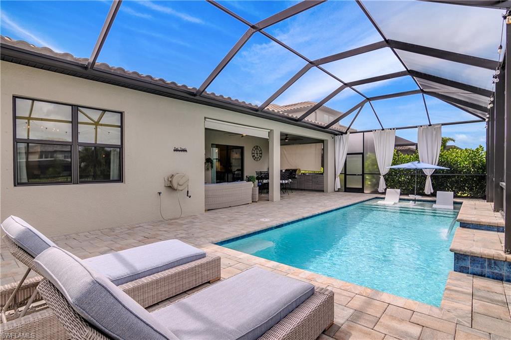 17570 Ashcomb Way Estero, FL 33928 - Photo 45 of 50 a view of a patio with couches table and chairs under an umbrella