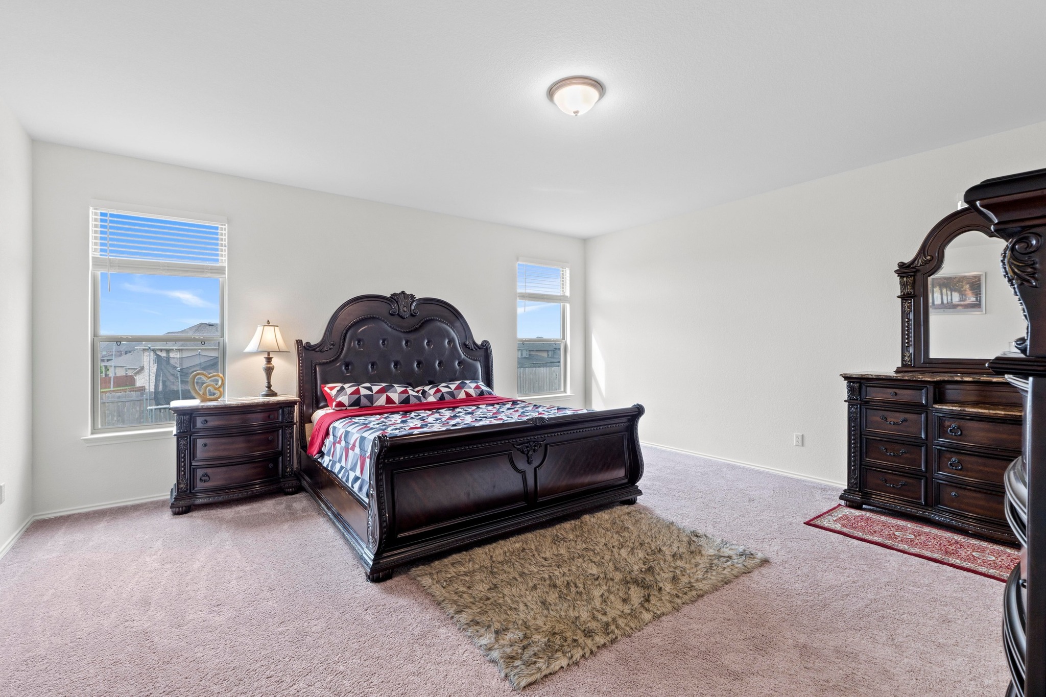 4729 San Rufo Drive Round Rock, TX 78665 - Photo 13 of 36 Spacious bedroom featuring light neutral wall tones, two large windows with horizontal blinds, a ceiling-mounted light fixture, and plush carpet flooring