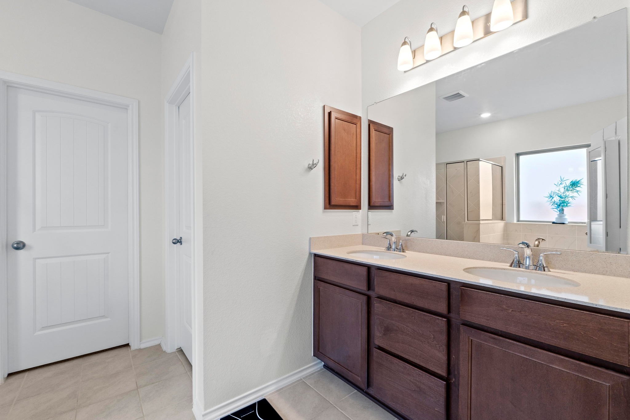 4729 San Rufo Drive Round Rock, TX 78665 - Photo 15 of 36 Bathroom featuring a dual vanity with dark wood cabinetry and a light-toned countertop, two integrated sinks with chrome faucets, and a large mirror with a four-light fixture