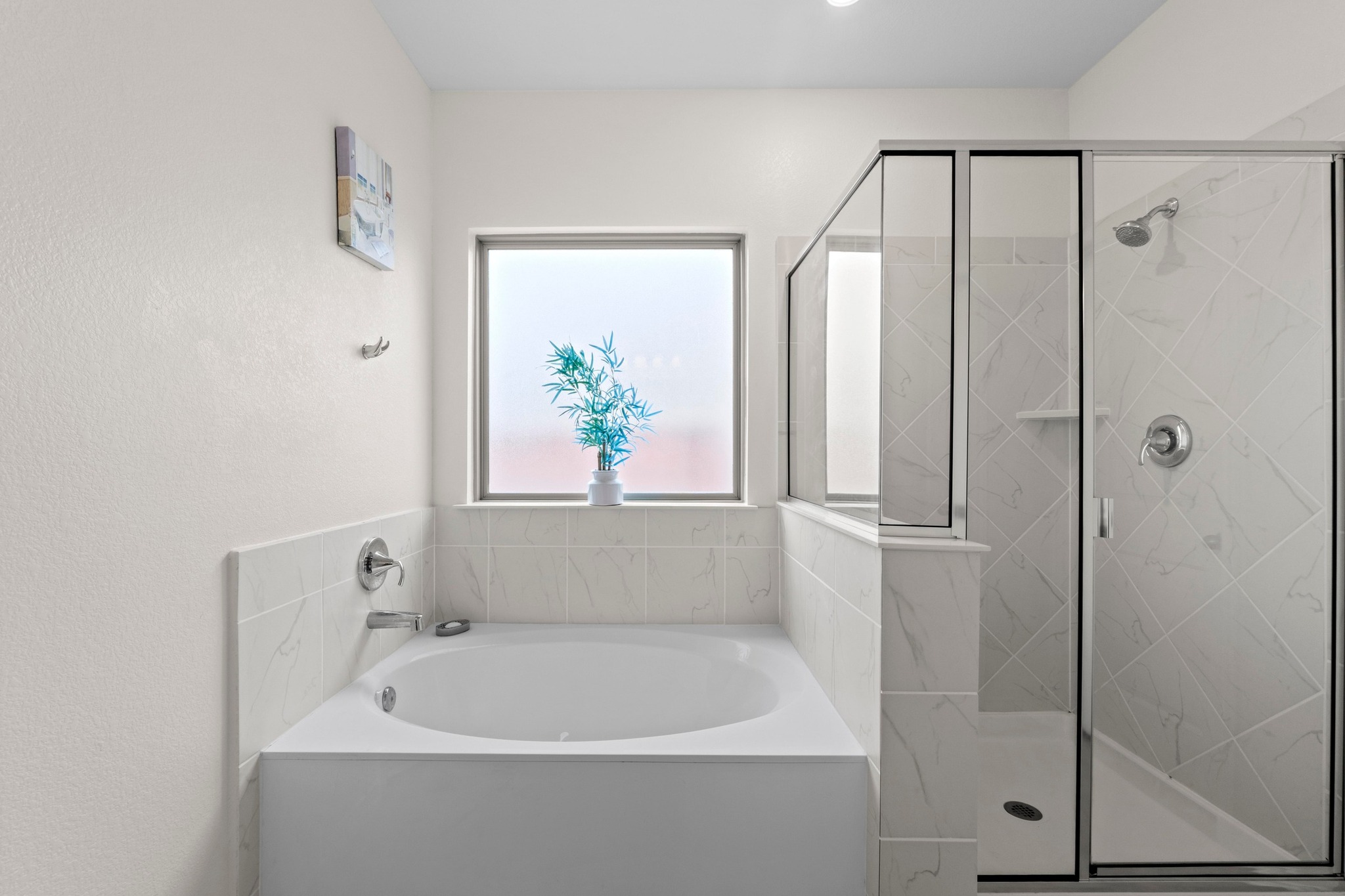 4729 San Rufo Drive Round Rock, TX 78665 - Photo 16 of 36 Bright bathroom featuring a built-in tub, separate glass-enclosed shower, frosted window, chrome fixtures, and white tile surrounds