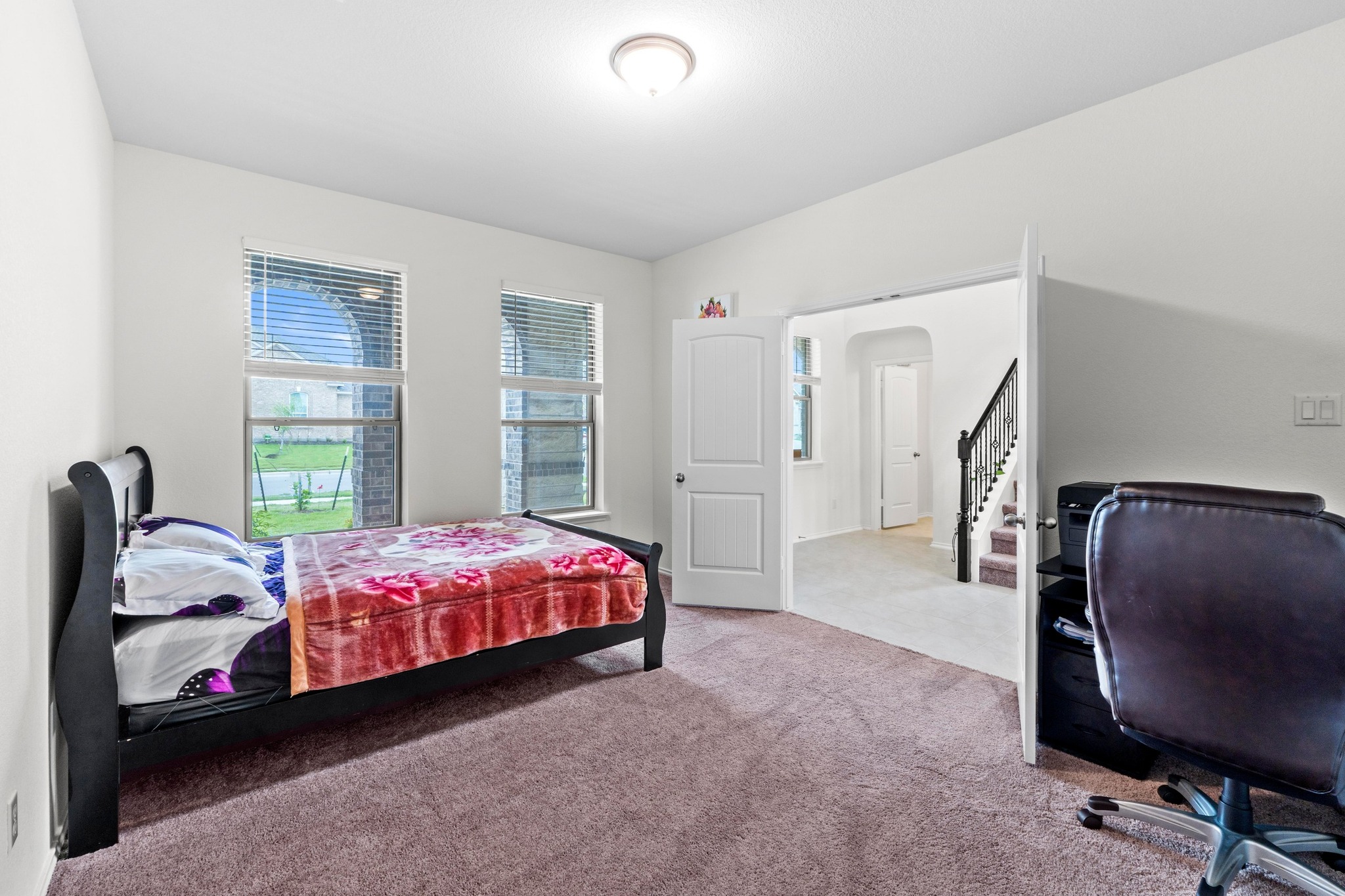 4729 San Rufo Drive Round Rock, TX 78665 - Photo 18 of 36 Carpeted room featuring two arched windows with blinds, a recessed ceiling light, and an open doorway leading to a staircase with dark banisters