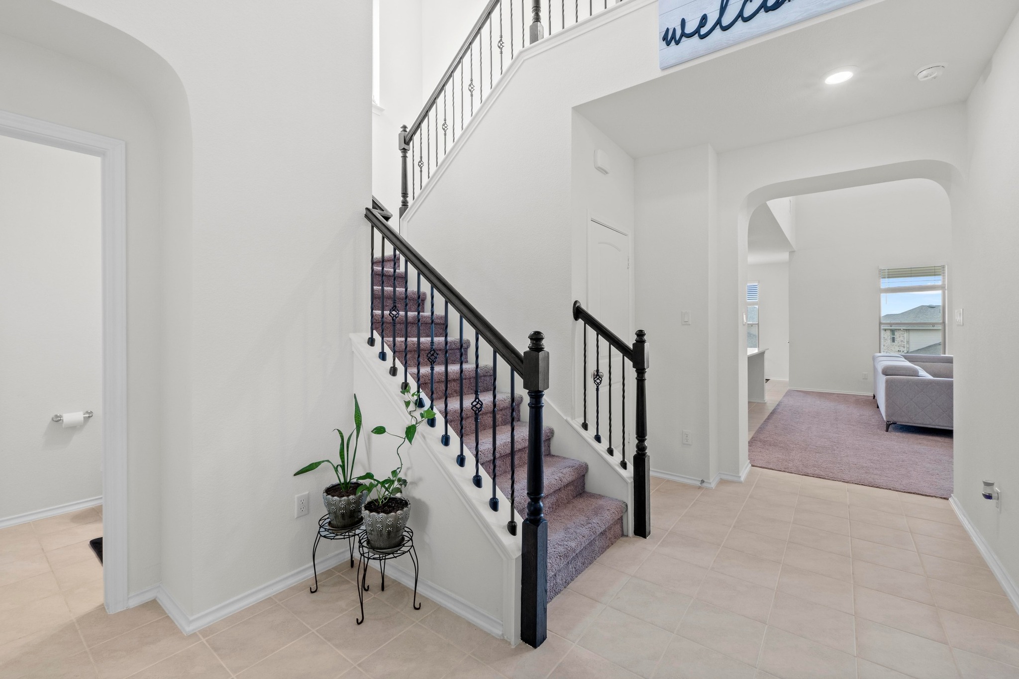 4729 San Rufo Drive Round Rock, TX 78665 - Photo 19 of 36 Foyer featuring a grand staircase with dark wood newel posts and wrought iron balusters, light-toned tile flooring, and a broad arched entryway