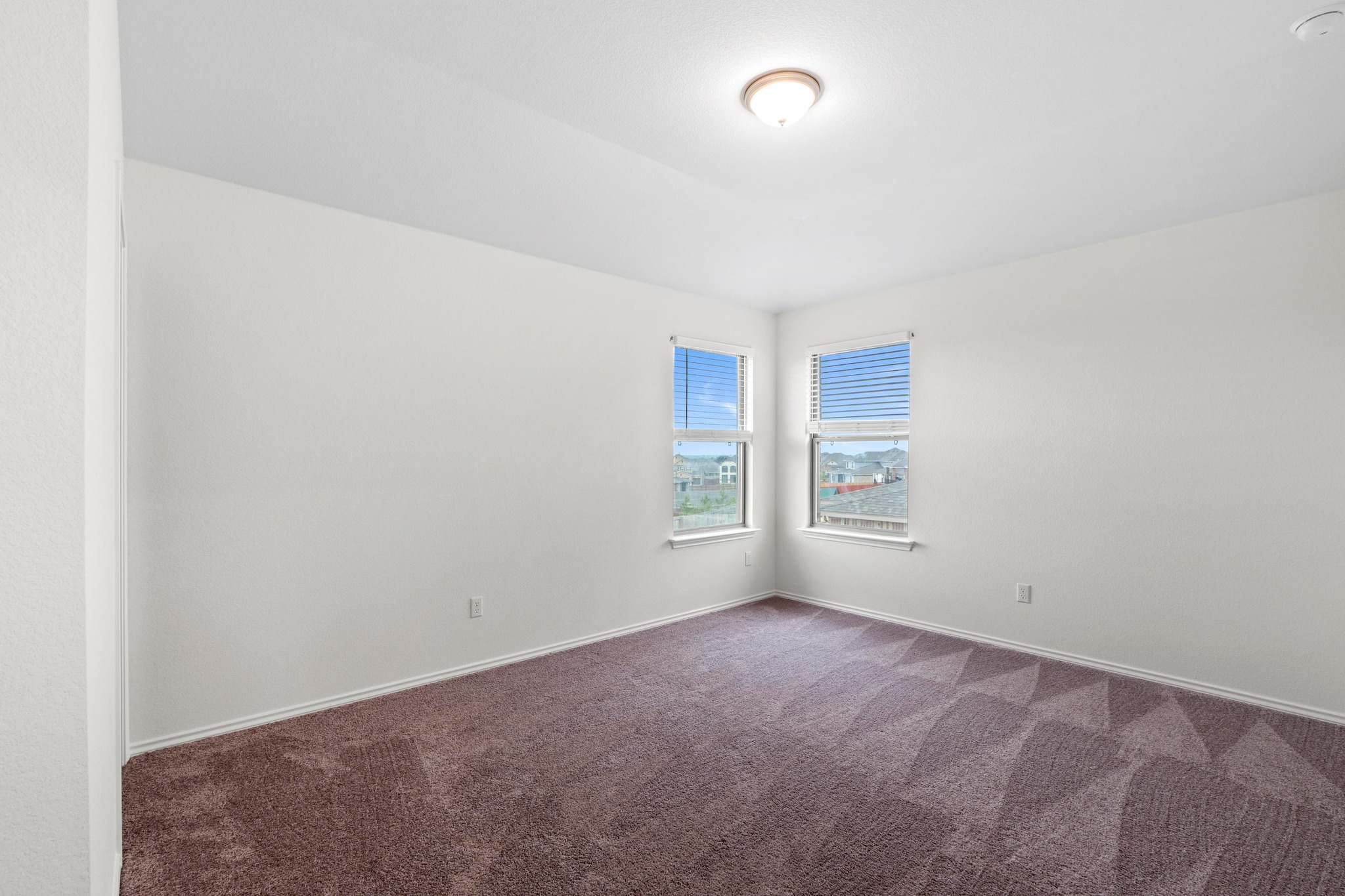 4729 San Rufo Drive Round Rock, TX 78665 - Photo 26 of 36 Room featuring two windows with blinds, neutral wall paint, and patterned carpet flooring