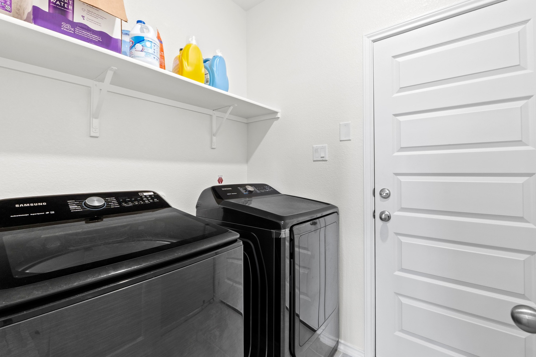 4729 San Rufo Drive Round Rock, TX 78665 - Photo 29 of 36 Dedicated laundry space featuring a white wall shelf, textured white walls, and a paneled interior door