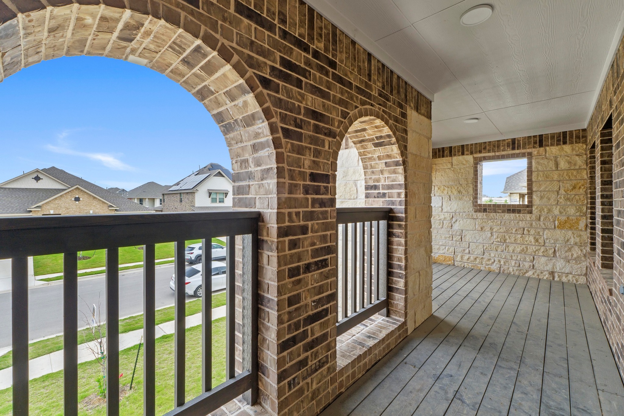 4729 San Rufo Drive Round Rock, TX 78665 - Photo 30 of 36 Second-story balcony featuring brick arches, stone accent walls, a dark wood-finish floor, and black railing