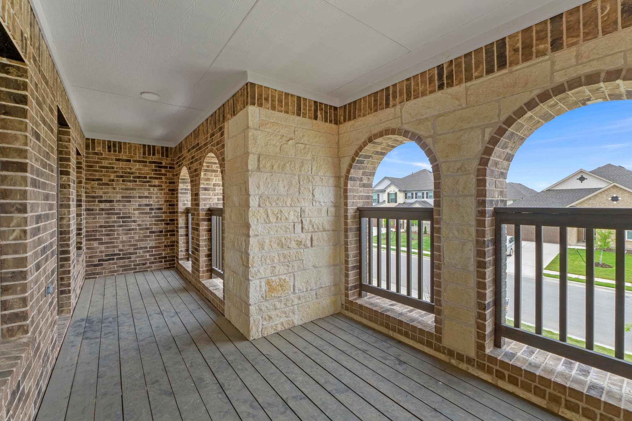 4729 San Rufo Drive Round Rock, TX 78665 - Photo 31 of 36 Balcony featuring arched openings with stone and brick accents, wood-finish flooring, and black railings