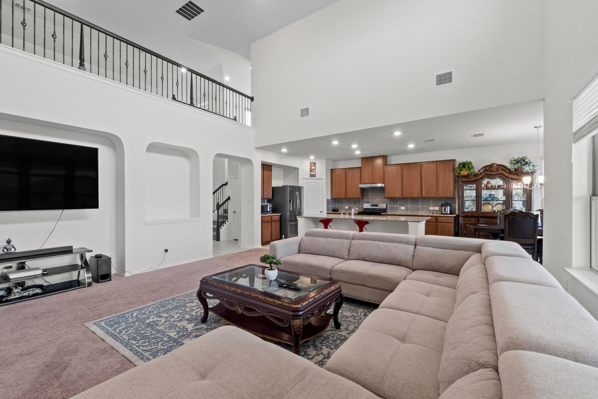 4729 San Rufo Drive Round Rock, TX 78665 - Photo 6 of 36 Vaulted living room featuring a second-story balcony with wrought iron railing, arched wall cutouts, recessed lighting, and an open concept kitchen
