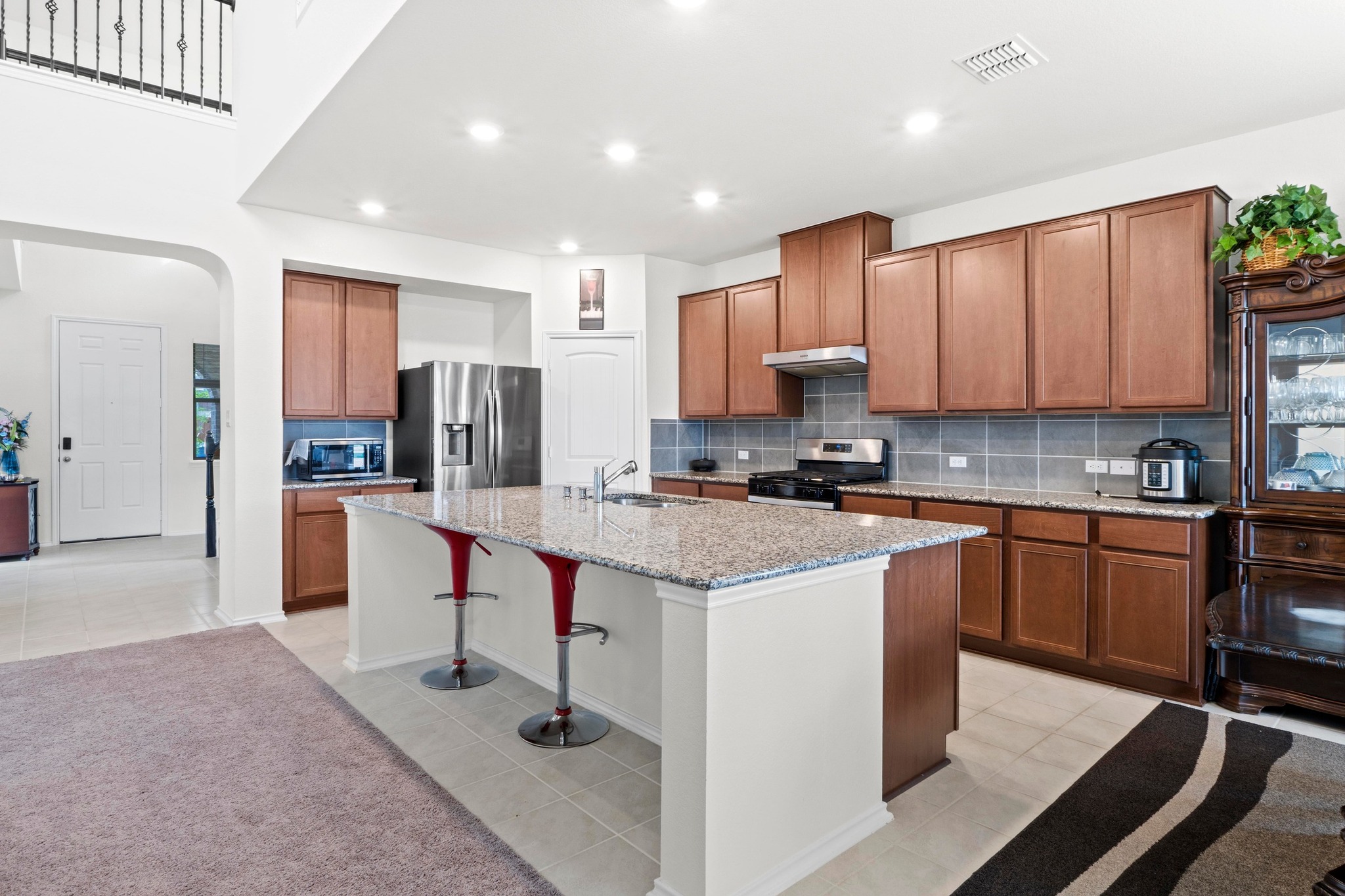 4729 San Rufo Drive Round Rock, TX 78665 - Photo 7 of 36 Expansive kitchen featuring a large island with a stone-finish countertop, rich wood cabinetry, stainless steel appliances, and tile flooring