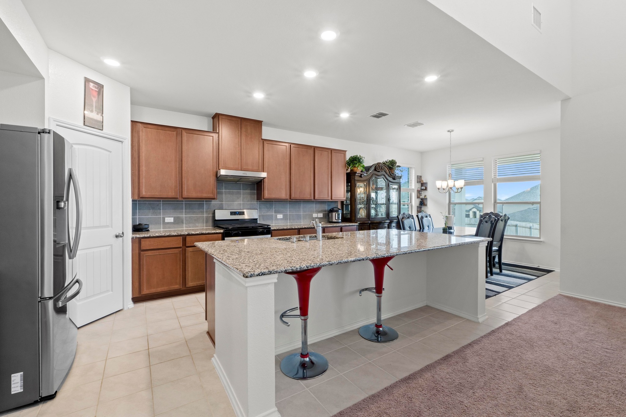 4729 San Rufo Drive Round Rock, TX 78665 - Photo 8 of 36 Open-concept kitchen featuring wood cabinetry, granite countertops, stainless steel appliances, and a tile backsplash