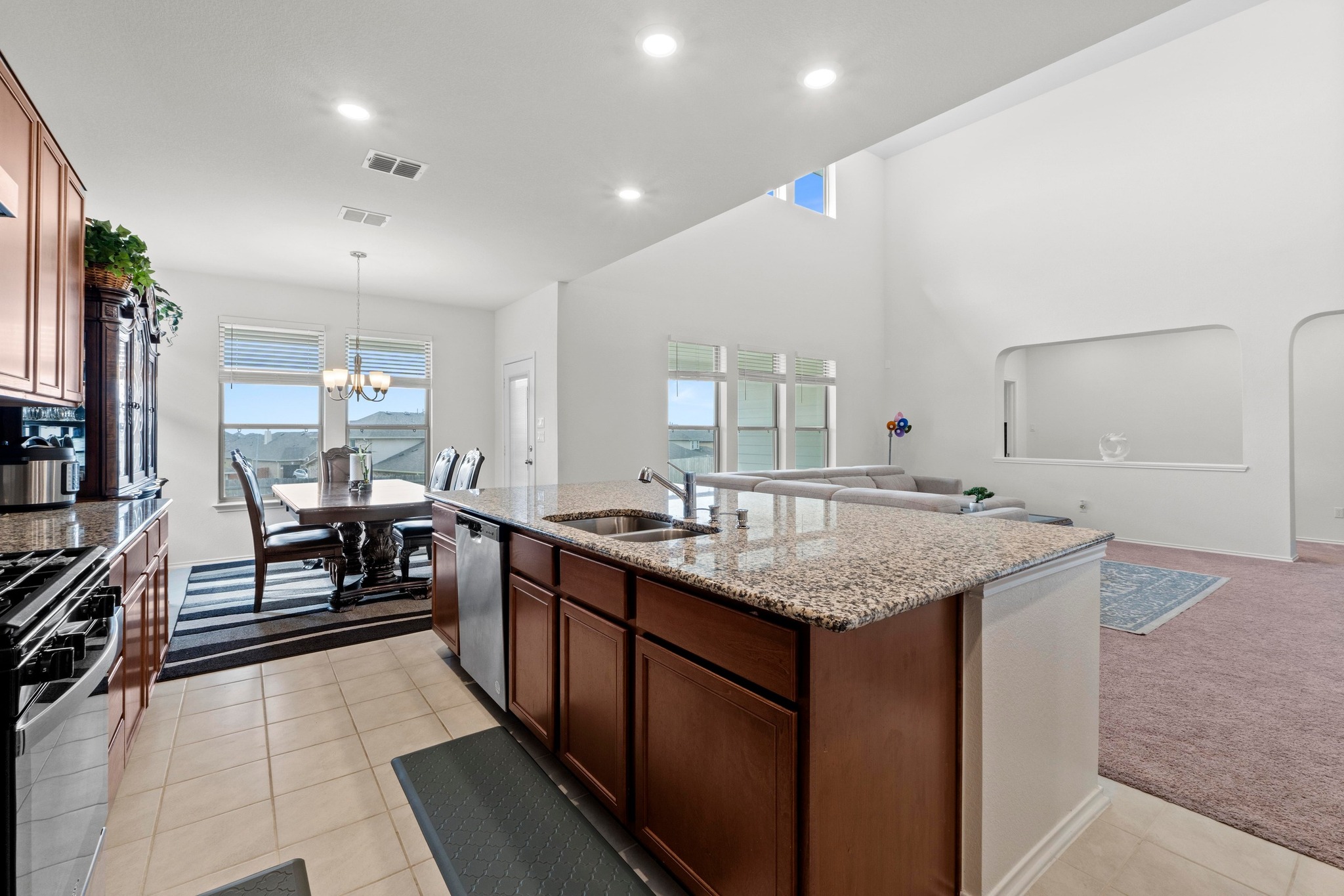 4729 San Rufo Drive Round Rock, TX 78665 - Photo 10 of 36 Kitchen island with granite countertops and integrated stainless steel sink, complemented by wood-finish cabinetry
