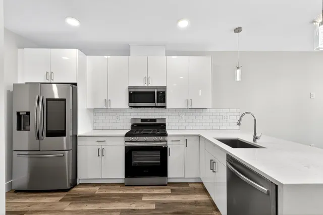 a kitchen with white cabinets and stainless steel appliances