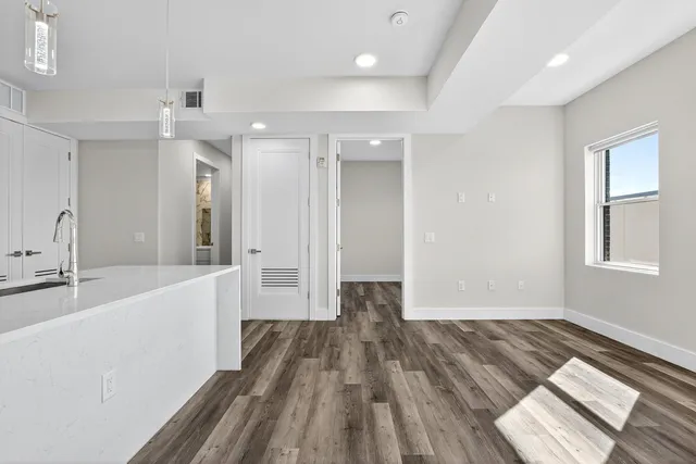 a view of a big room with wooden floor and windows