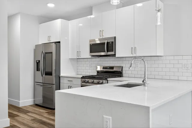 a kitchen with stainless steel appliances a microwave a sink and cabinets