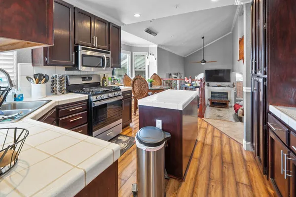 a kitchen with stainless steel appliances granite countertop a stove top oven a sink dishwasher a refrigerator and cabinets with wooden floor