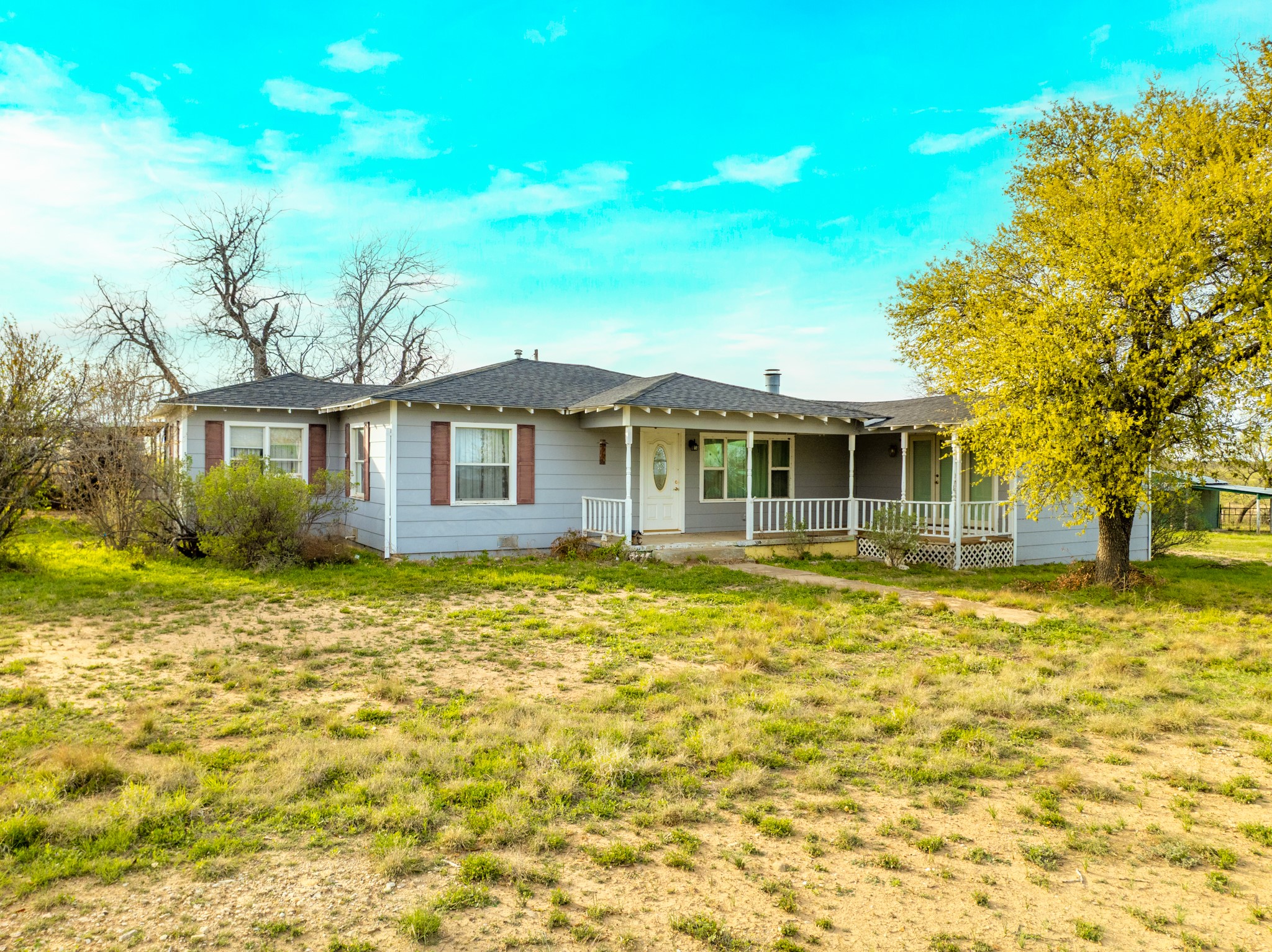 2145 County Road 320 Lohn, TX 76852 - Photo 2 of 40 Ranch-style home featuring covered porch, a front lawn, and roof with shingles
