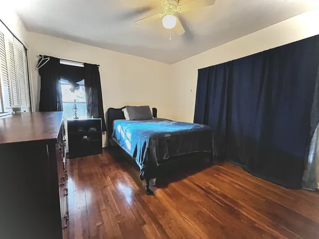 a bedroom with a bed and a large mirror with wooden floor