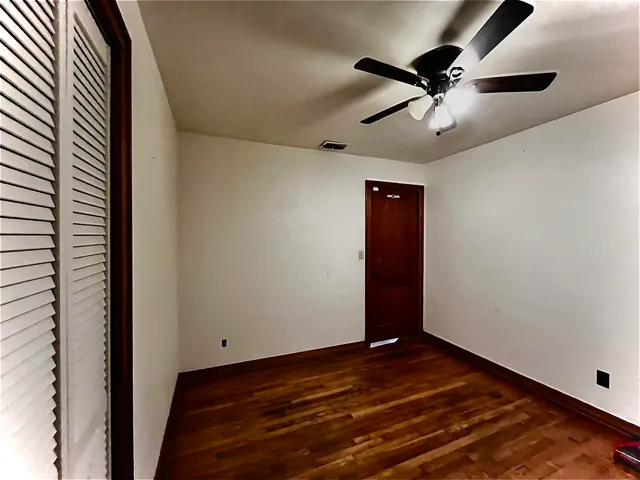 an empty room with wooden floor a ceiling fan and staircase