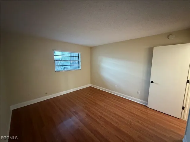 an empty room with wooden floor and closet area