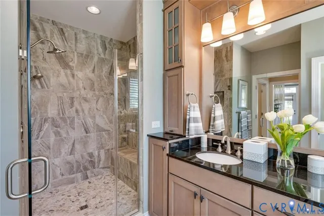 a bathroom with a granite countertop sink a mirror a vanity and a shower