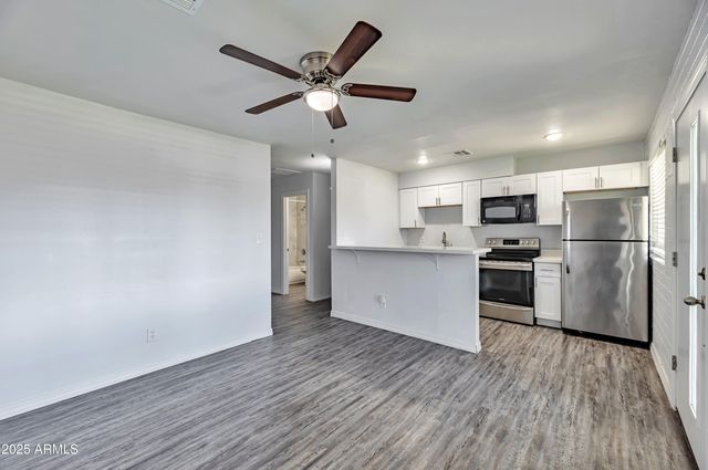 a view of kitchen with stainless steel appliances refrigerator stove microwave and cabinets