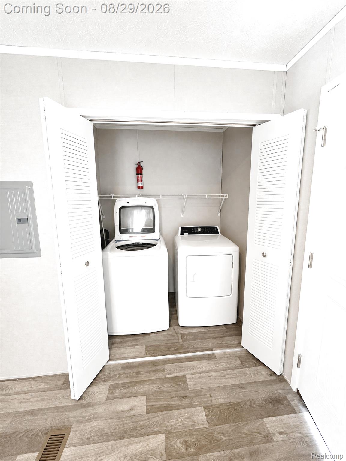 46000 Geddes Road, Unit 520 Canton, MI 48188 - Photo 26 of 29 Dedicated laundry closet featuring a washer and dryer, louvered bi-fold doors, wood-finish flooring, and wire shelving