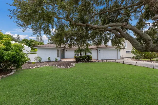 a view of a white house with a big yard and large tree