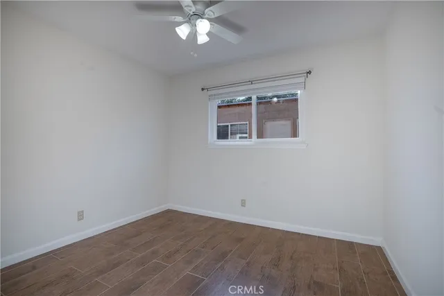 an empty room with wooden floor and fan