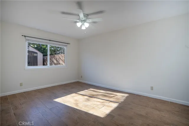 an empty room with wooden floor chandelier and windows